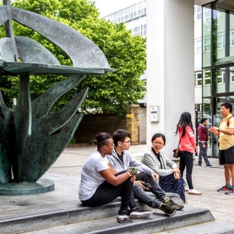 university students sat near sculpture