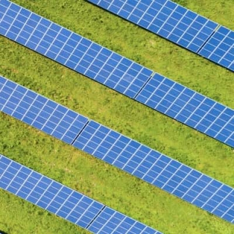 Aerial picture of solar panels in a field, next to a road