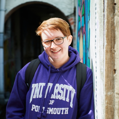Student in purple hoodie standing in back alleys