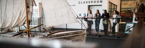 Female students in museum looking at antique boat