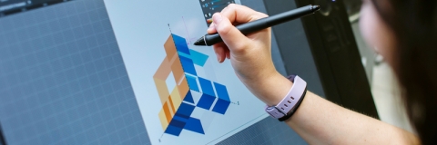 A student drawing a geometric design on a Wacom tablet screen