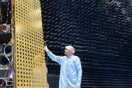 Person inspecting a satellite component in a clean room